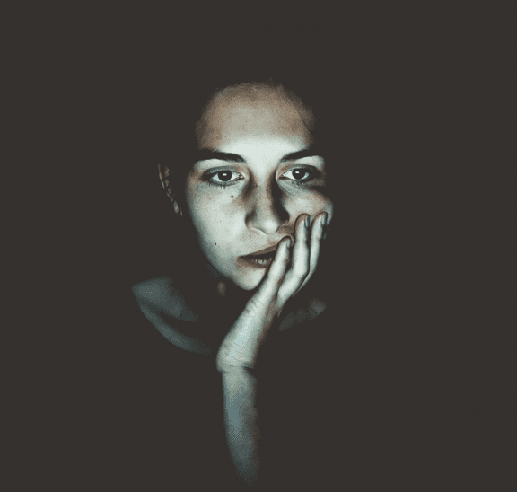 Woman sitting in dark with zoom fatigue. Credit Niklas Hamann